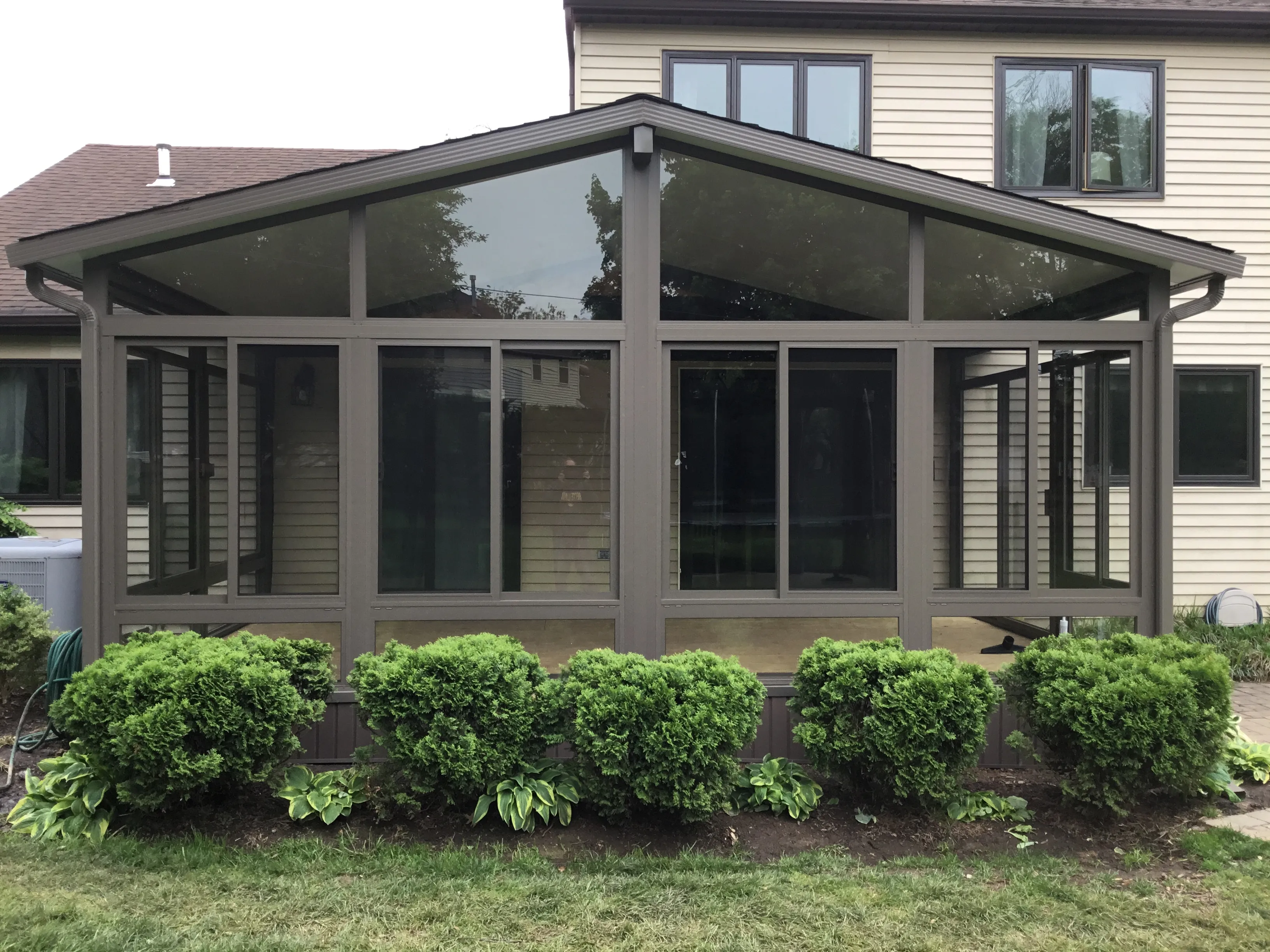 Bronze framed gable roof sunroom with clipped hedging